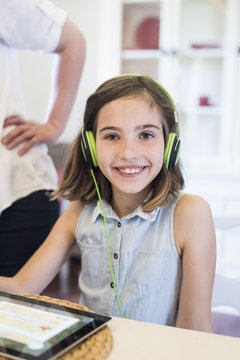 Portrait of smiling girl with digital tablet wearing headphones