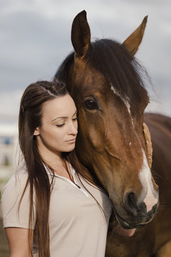Young woman with brown horse outdoors