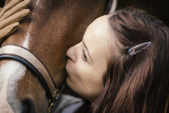 Young woman kissing brown horse