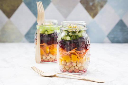 Two glasses of rainbow salad with chick-peas and different vegetables