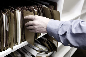 Businessman Reaching Hand for Files on Shelf