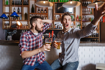 Young people with beer watching football in a bar