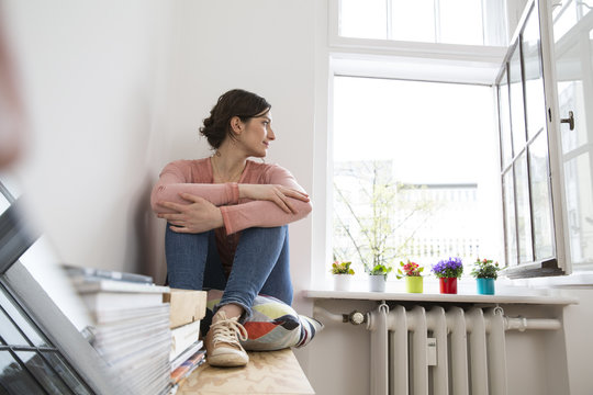 Young woman sitting at the window looking out