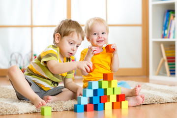 Preschooler children playing with colorful toy blocks. Kid playing with educational wooden toys at kindergarten or day care center. Toddler in nursery.