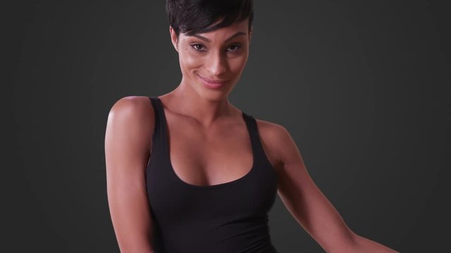 Sexy woman in tight black dress dancing on grey background. Close-up of African American woman.