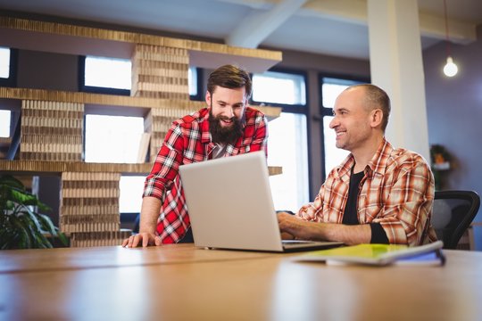 Creative Male Coworkers Discussing Over Laptop 