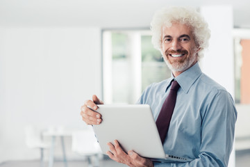 Fototapeta na wymiar Confident businessman holding a laptop