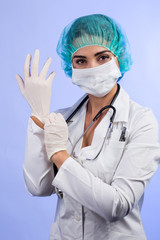 Medico donna con guanti, camice mascherina  e cuffietta verde si sistema unguento prima di operare - isolata su sfondo  chiaro