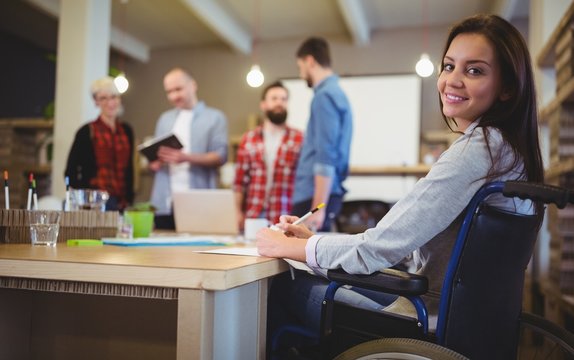 Confident disabled businesswoman writing at desk 