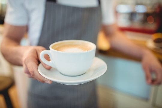 Midsection of barista serving coffee at shop