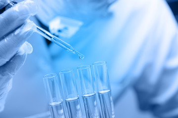 scientist  dropping chemical liquid to flask with lab glassware