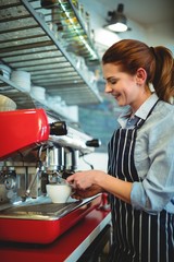 Happy owner using coffee maker at cafe