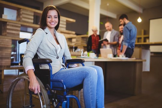 Confident disabled businesswoman by desk 