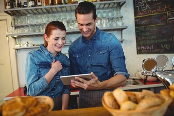 Happy co-workers using tablet computer at cafe