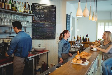 Female customer talking with barista at cafe