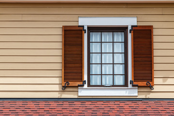 Window with brown shutters on the wooden wall of the building.