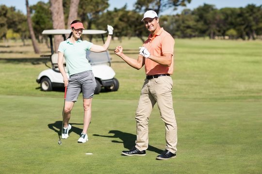 Full length portrait of golfer couple celebrating success 