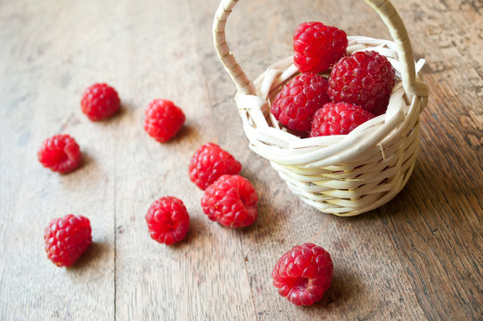 framboises et petit panier en osier sur table en vieux bois