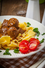 Tagliatelle, meatballs in dark sauce and tomato.