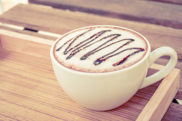 cup of cocoa with foam on wood table.vintage tone