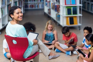 Smiling teacher with children using digital tablets