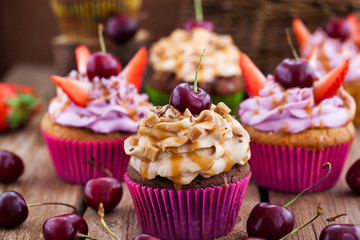 Delicious cupcakes decorated with caramel and fresh berries