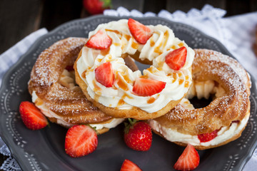 Cream puff rings decorated with fresh strawberry and caramel sau