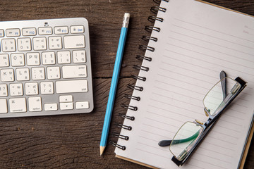 Top view office desk with open book and keyboard and eyeglasses