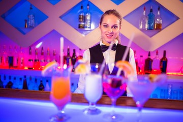 Pretty barmaid standing at bar counter