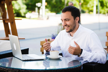 Work and relax. Online conference. Businessman dressed in shirt working with laptop, talking by skype at the park cafe outdoors - obrazy, fototapety, plakaty