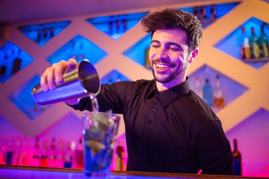 Barkeeper pouring cocktail in glass