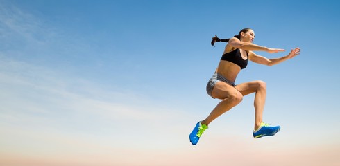 Fototapeta premium Composite image of sporty woman jumping
