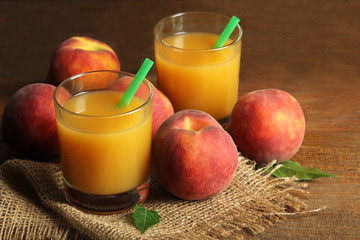 delicious and juicy peaches on wooden background with burlap and cups of peach juice with the boiler tube