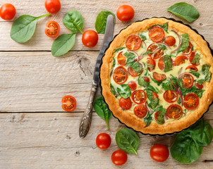 Summer outdoor tart, pie of fresh vegetables - tomatoes, spinach and red onion with cream and...