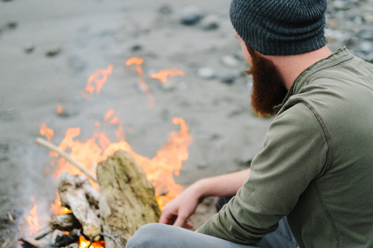 Over the shoulder view of bearded man by campfire