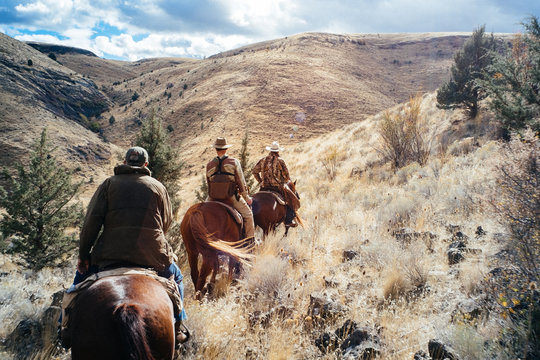 Three men riding up mountain on horseback
