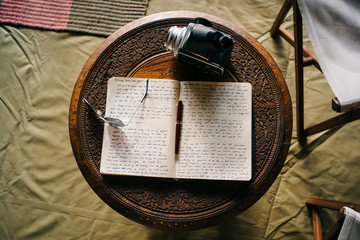 Overhead view of handwriting in notebook and camera on table