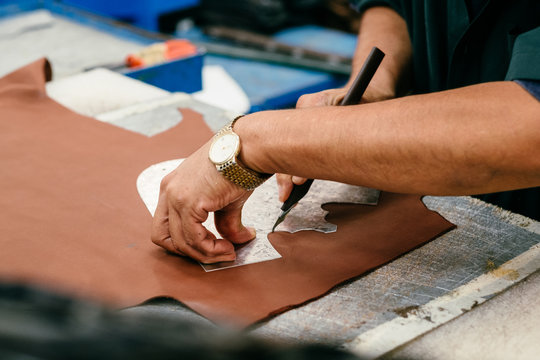 Person in workshop using template, cutting leather