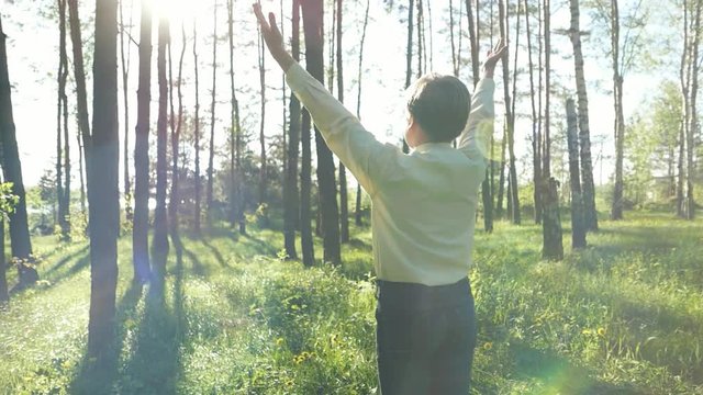 Child boy teen in the sunlight, stretching his arms to the sun, slow motion. Happiness, good mood. Environment and Ecology. Healthy lifestyle