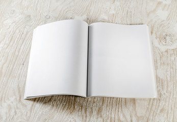 Fototapeta premium Blank opened book with soft shadows on light wooden background. Responsive design template. Mock-up for your design. Top view.