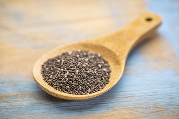 black chia seeds on wooden spoon