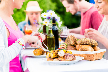 Freunde essen Grillwürste und Fleisch auf Garten- oder Grillfest