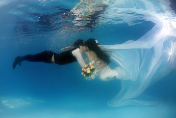 Fototapeta na wymiar Bride and groom, underwater wedding in a pool
