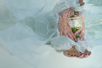 Bride's hands and feet, flowers, underwater wedding in pool