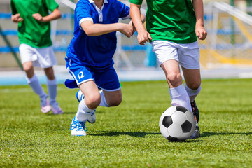 Fototapeta na wymiar Young boys kicking soccer football on the sports field. Youth blue and green teams tournament competition