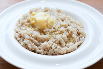 A healthy Breakfast of barley porridge with butter served in a white plate