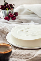 Fototapeta na wymiar Vanilla bavarian mousse cake with cream cheese and whipped cream. White plate. Cherries on the background.