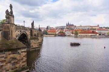Fototapeta na wymiar Vltava river and Charles Bridge at cloudy sky with Prague castle in the background, Prague, Czech Republic