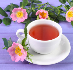 Obraz na płótnie Canvas Cup of tea and wild rose flower on purple boards