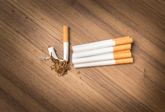 stop smoking Tobacco ,tear cigarette detrimental on wood background , and space for add text above , select focus front cigarette , (Open light cigarettes)